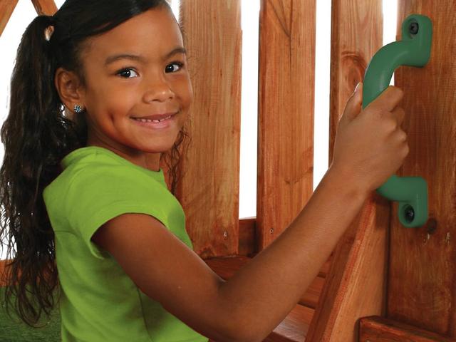 A girl holding a green safety handle on a play deck