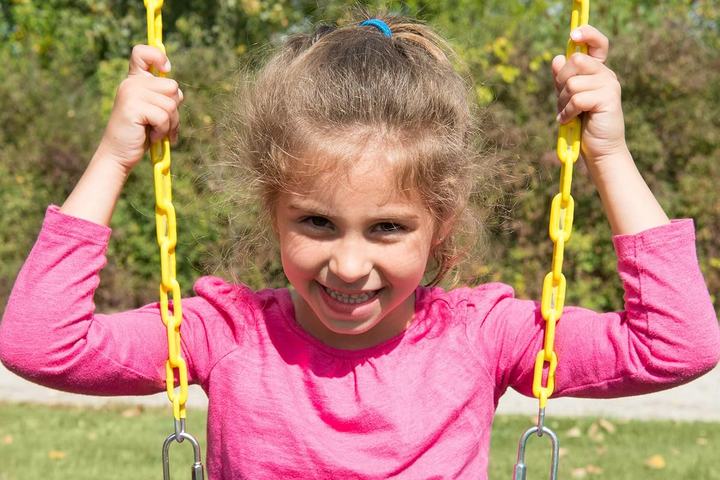 A girl on a belt swing holding yellow coated chains